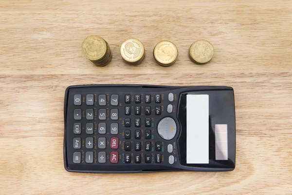 Монети, олівець і калькулятор на фоні дерева — стокове фото
