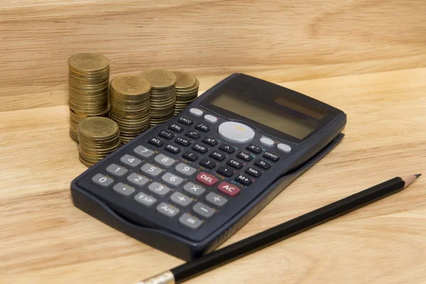 Monety, ołówek i kalkulator na tle drewna — Zdjęcie stockowe