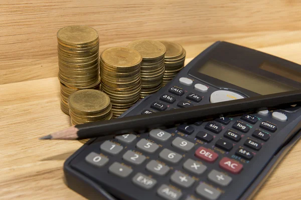 Монеты, карандаш и калькулятор на деревянном фоне — стоковое фото