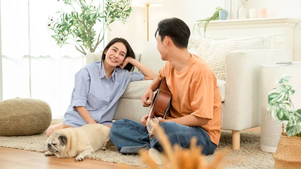 Çift evde köpekleriyle birlikte yerde oturuyor. Biri dinlenirken gitar çalar..