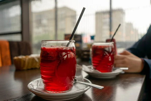 İki çilekli içecek (meyve suyu, komposto, sıcak şarap) bir kafede güzel bir bardakta tüplü olarak masanın üzerindedir. Tarih illüstrasyonu, kafe