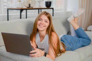 Evde dizüstü bilgisayarla ödev yapan genç kız öğrenci, çevrimiçi öğrenme, uzaktan eğitim