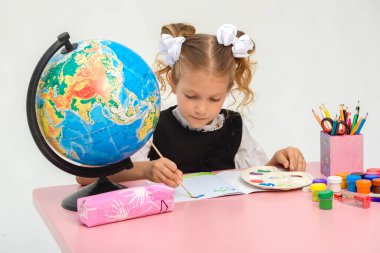 Gülümseyen güzel kızın portresi ilginç dersler sırasında öğrenme ve test yapma. Akıllı kız masada oturuyor, kameraya bakıyor ve poz veriyor. Öğrenciler arka planda çalışıyor