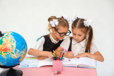 Beyaz arka planda ödev yapan iki küçük kızın portresi...