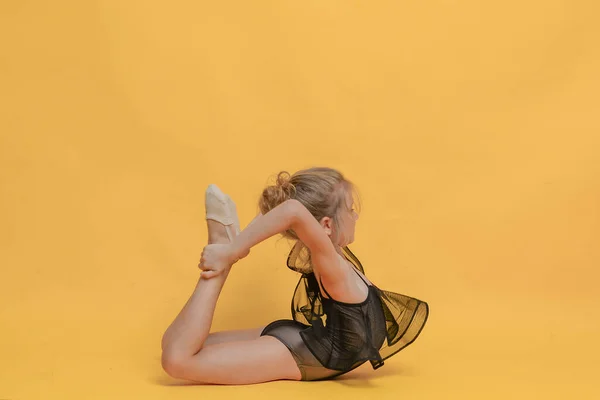 Pequena Ginasta Menina Flexível Fazendo Exercícios Diferentes Posa Fundo Amarelo — Fotografia de Stock