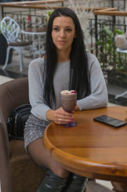 Genç ve güzel bir kadın bir kafede kahve içiyor.