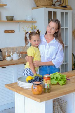 Anne ve küçük kızı mutfakta birlikte sağlıklı yemekler pişiriyorlar.