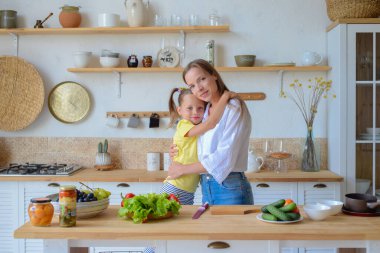 Anne ve kızı evdeki mutfakta birlikte yemek pişiriyorlar.