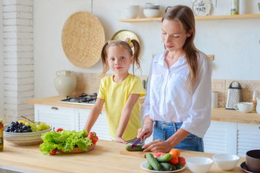 Anne küçük kızına mutfakta sağlıklı yemek pişirmeyi öğretiyor.