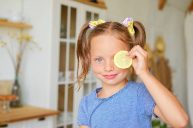 Sevimli küçük kız mutfakta limonlu çay içiyor. Oynuyor ve eğleniyoruz.