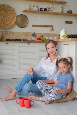 Anne ve küçük kızı mutfakta çay içip birlikte kahvaltı ediyorlar. aile portresi