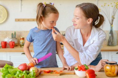 Anne küçük kızına mutfakta sağlıklı yemek yapmayı öğretiyor.