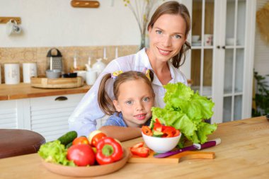 Anne küçük kızına mutfakta sağlıklı yemek yapmayı öğretiyor.