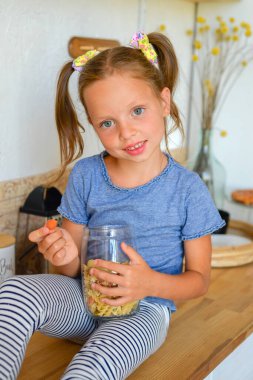 Mutfaktaki küçük tatlı kız. Sağlıklı yiyecekler hazırlar ve yer.