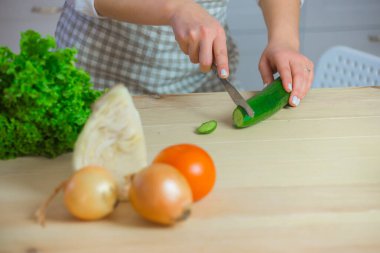 Kadın salatalığı yakın plan kesiyor. diyet ve kilo kaybı kavramı