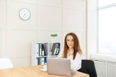 Güzel genç iş kadını ofisteki bilgisayarın başında çalışıyor. Bağımsız uzaktan çalışma