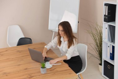 Güzel genç iş kadını ofisteki bilgisayarın başında çalışıyor. Bağımsız uzaktan çalışma