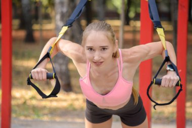 Spor salonunda trx fitness kayışlarıyla şınav çeken bir kadın sağlıklı yaşam tarzı egzersiz konsepti.