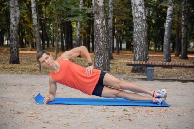 Erkek koşucu eğitimi. Parkta kaslarını esneten erkek sporcu. Sağlıklı, sağlıklı, sağlıklı bir yaşam tarzı. Spor, kardiyo, egzersiz konsepti