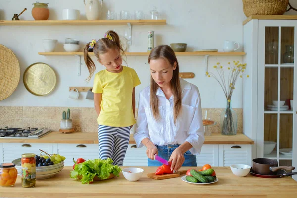 Anne küçük kızına mutfakta sağlıklı yemek pişirmeyi öğretiyor.