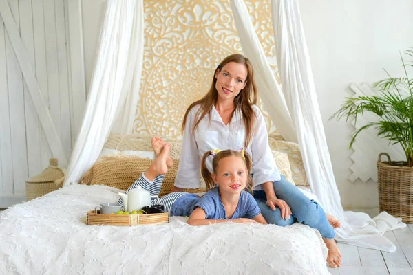 Mutlu anne ve küçük kız birlikte sıcak çay içip evde kahvaltı ediyorlar.