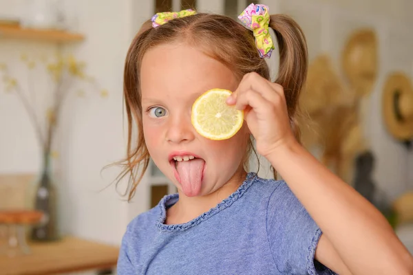 cute little girl drinking tea with lemon in the kitchen. playing and having fun