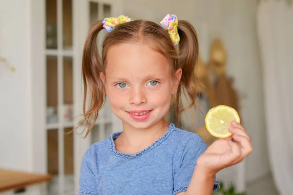 cute little girl drinking tea with lemon in the kitchen. playing and having fun