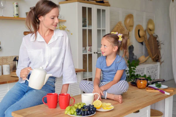 Anne ve küçük kızı mutfakta çay içip birlikte kahvaltı ediyorlar. aile portresi