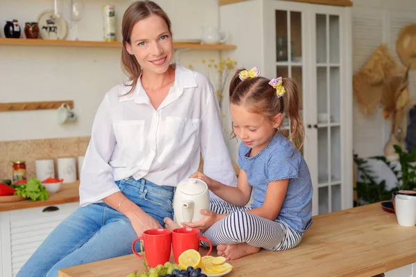 Anne ve küçük kızı mutfakta çay içip birlikte kahvaltı ediyorlar. aile portresi