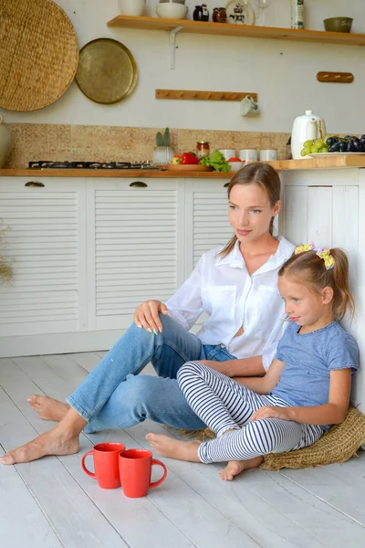 Anne ve küçük kızı mutfakta çay içip birlikte kahvaltı ediyorlar. aile portresi