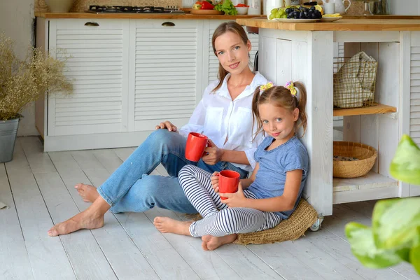 Anne ve küçük kızı mutfakta çay içip birlikte kahvaltı ediyorlar. aile portresi