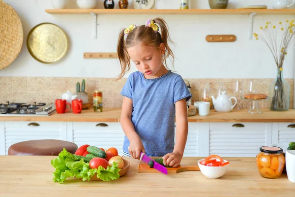 Mutfaktaki küçük kız salata için sebze kesiyor. Doğru beslenme ve vejetaryenlik kavramı