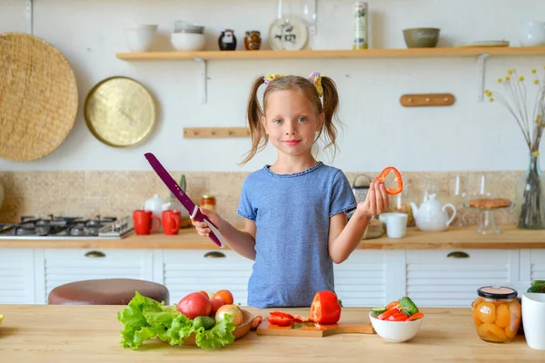 Mutfaktaki küçük kız salata için sebze kesiyor. Doğru beslenme ve vejetaryenlik kavramı
