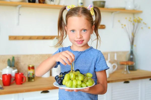 Mutfaktaki küçük tatlı kız. Sağlıklı yiyecekler hazırlar ve yer.