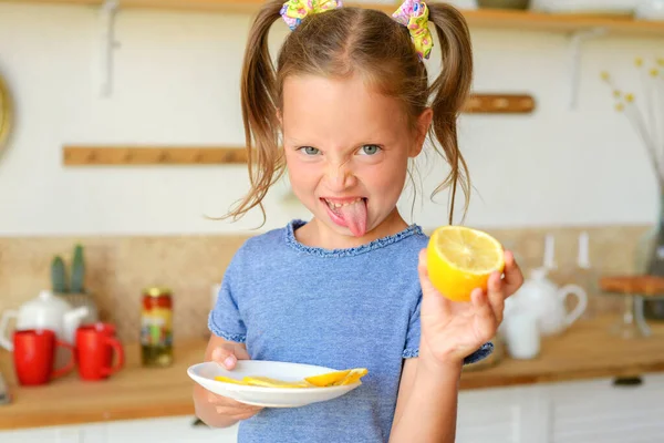 Mutfaktaki küçük kız limonlu çay içiyor.