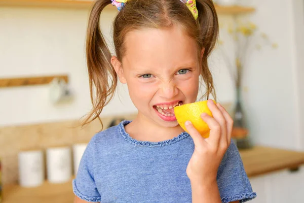 Mutfaktaki küçük kız limonlu çay içiyor.