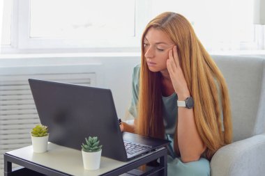 Evde dizüstü bilgisayarla çalışan genç bir kadın.