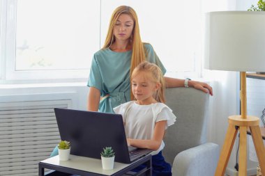 Anne ve kızı dizüstü bilgisayarda ödev yapıyor. Online eğitim. Mutlu bir aile.