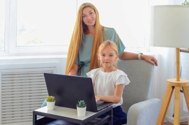 Anne ve kızı dizüstü bilgisayarda ödev yapıyor. Online eğitim. Mutlu bir aile.