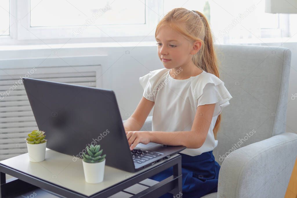 Pretty stylish schoolgirl studying homework math during her online lesson at home, social distance during quarantine, self-isolation, online education concept, home schooler