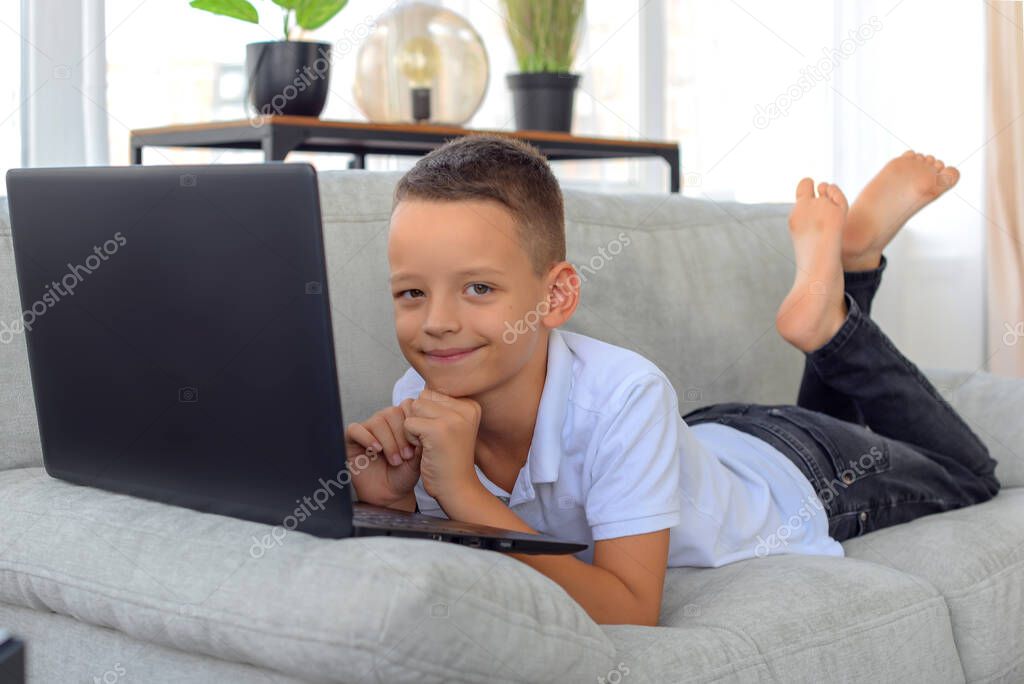 schoolboy boy with laptop does homework. online learning