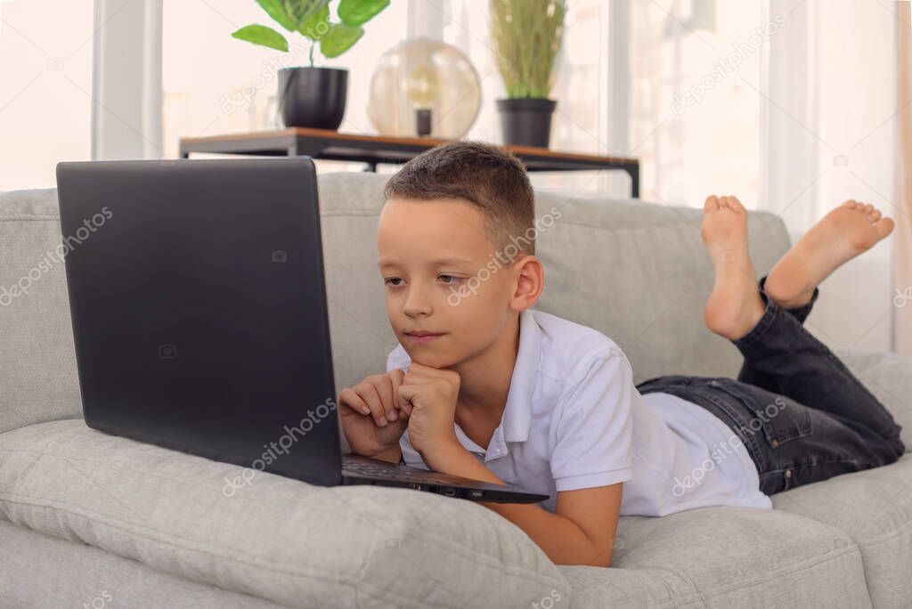 schoolboy boy with laptop does homework. online learning