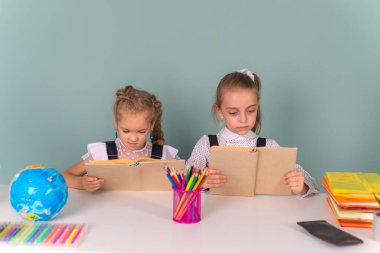 Okula dönelim. Masadaki iki kız tablet bilgisayar ve kitaplarla ödev yapıyor. Kalemler, kitaplar. İlkokuldan çocuklar. Sonbaharın ilk günü.