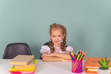 Okula dön ve mutlu ol! Şirin, çalışkan bir çocuk kapalı bir masada oturuyor. Sınıfta çalışan kız tahtanın arka planında. Kız bir kitap okuyor..