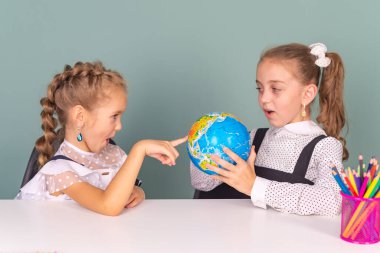 İki küçük kız öğrenci, okulda, masada ders çalışıyor. Sınıfta oku ve yaz. öğrenme kavramı