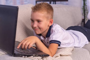 Kulaklıklı çocuk dizüstü bilgisayar kullanıyor ve evdeki video öğretmeniyle internetten ders çalışıyor. Evde eğitim, uzak öğrenim