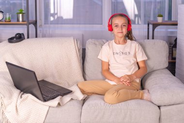 Dizüstü bilgisayarı ve kitabı olan kız öğrenci ev ödevi yapıyor. Evde eğitim kavramını karantinaya al