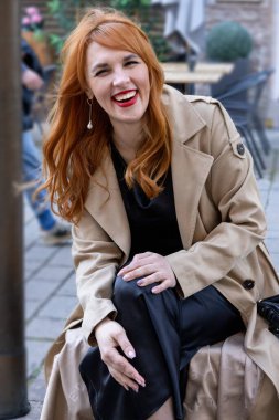 Şehirli kadın gülümsüyor, neşeli genç kadın günlük giysiler içinde canlı şehir kafesinde yakalandı.