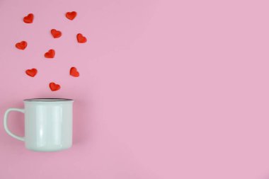 Dağılmış kalpleri olan nane kupası, pembe arka planda, küçük kırmızı kağıt kalpli minimalist bemol.,