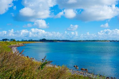 Grassy Bluff 'tan Turkuaz Koyu' nu Temizle, Rocky Edge Çerçeve Suyu, Yüksek ve Uzak Kıyı Bulutları Seyahat İçin İdeal Kıyı Dinginliği